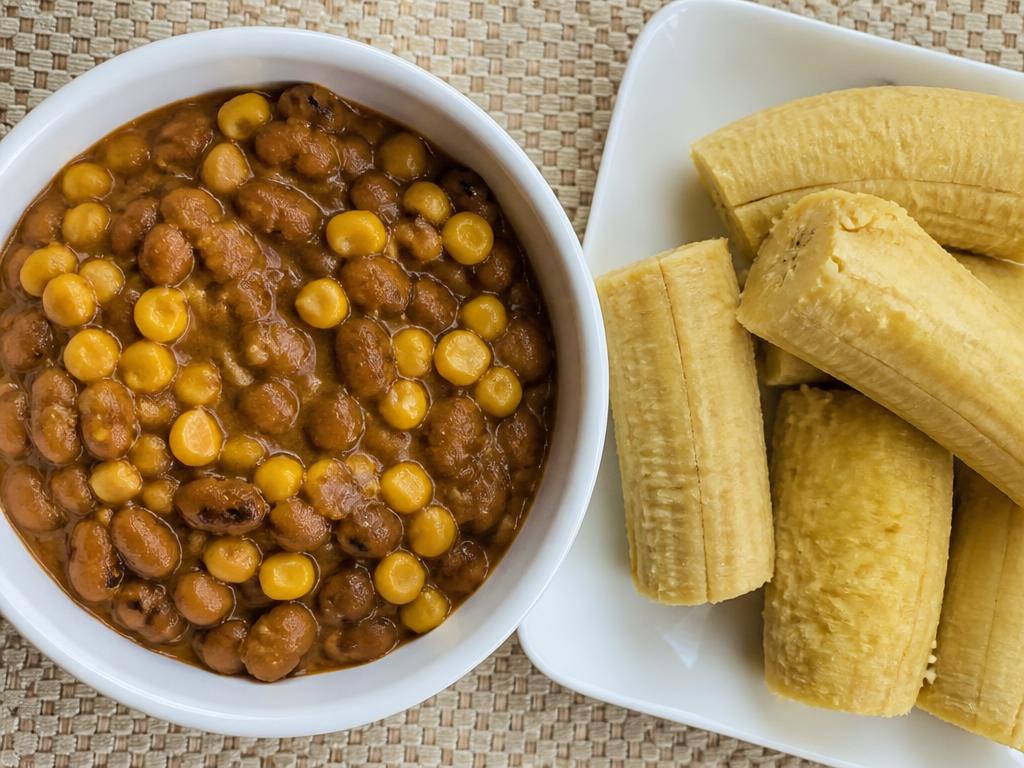 Bowl of Nigerian adalu beans and sweetcorn served with boiled plantain