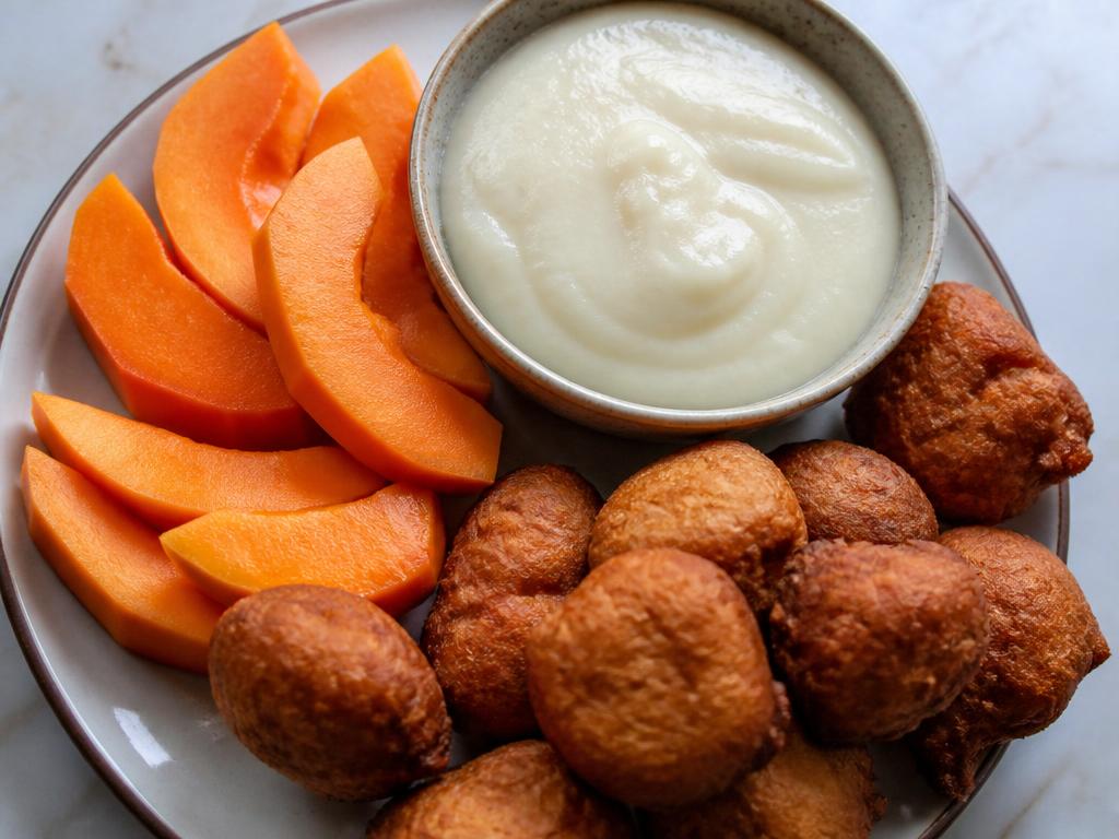 Nigerian akara bean cakes served with a bowl of pap and sliced pawpaw
