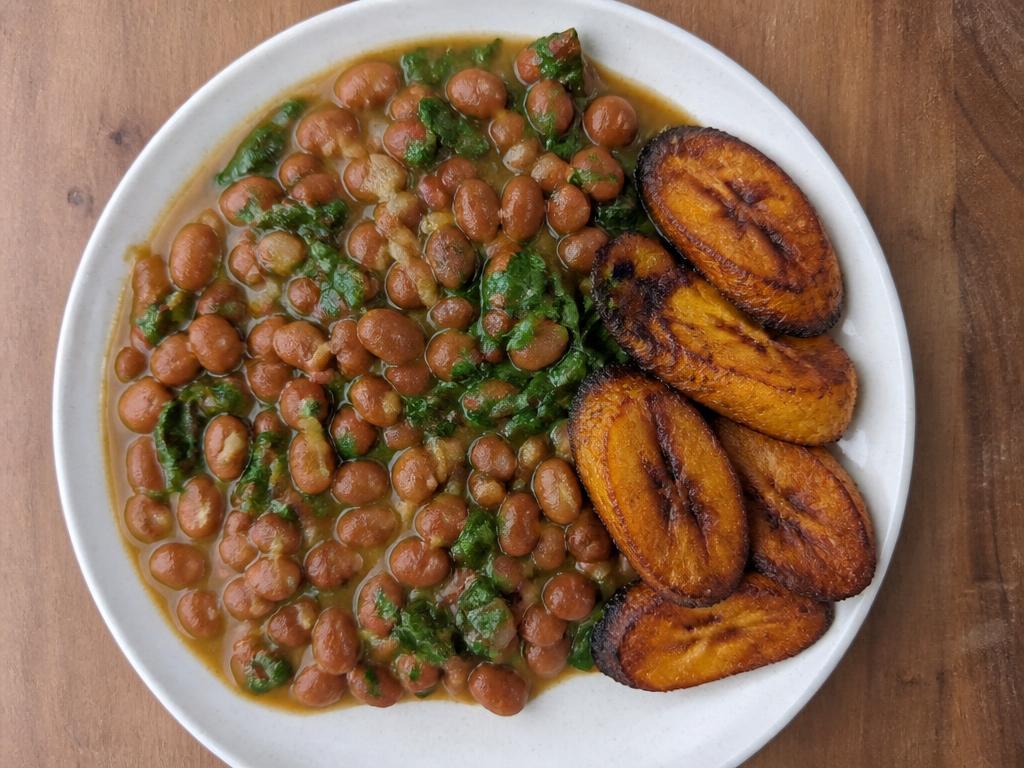 Plate of Nigerian beans and spinach stew served with fried ripe plantain