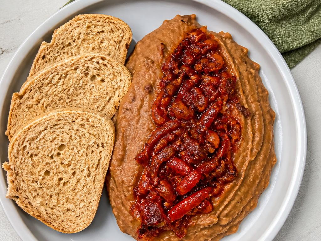 Plate of Nigerian ewa agoyin mashed beans with pepper sauce and wholemeal bread