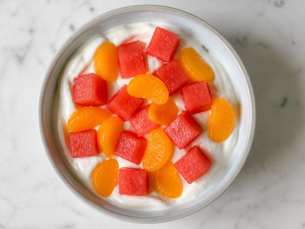 Pot of watermelon and orange pieces with plain yoghurt