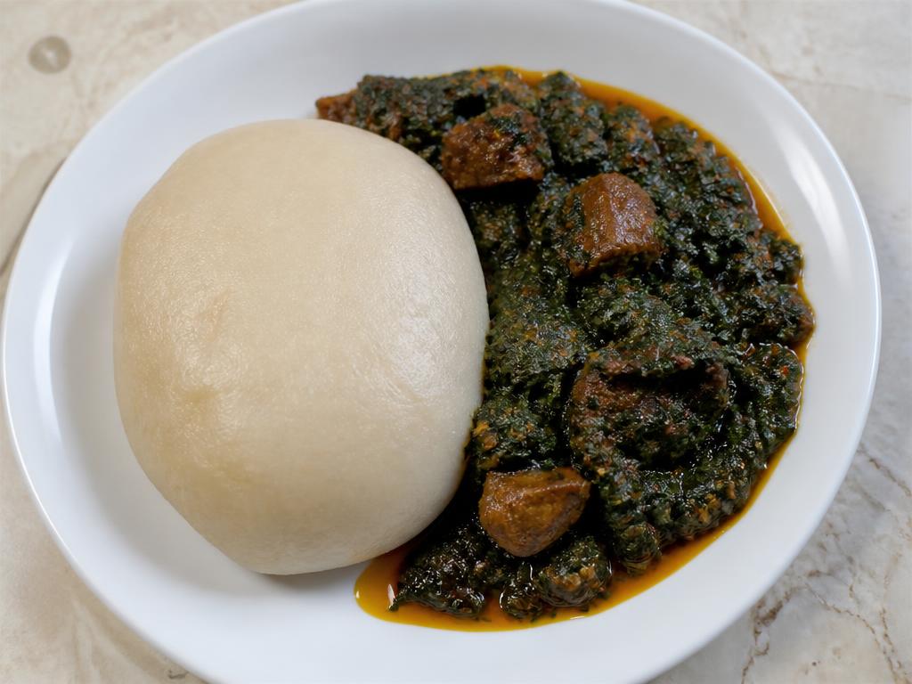 Plate of Nigerian tuwo alkama wheat meal with efo riro spinach stew and beef